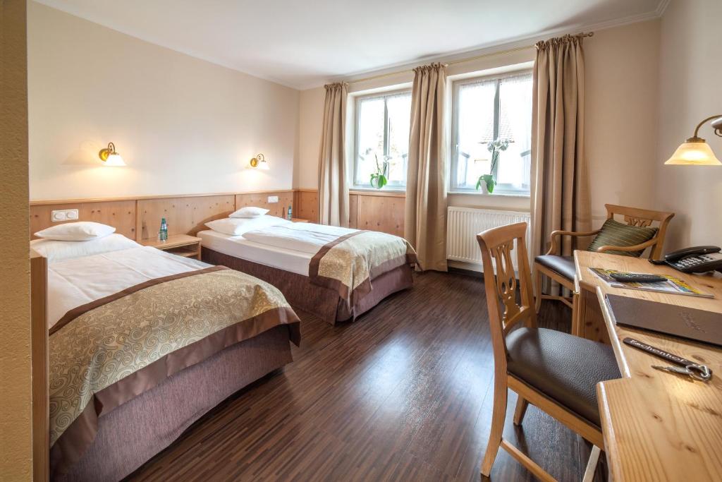 a hotel room with two beds and a desk at Hotel Eschenhof in Kirchheim