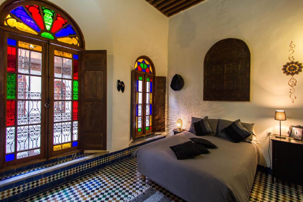 een slaapkamer met een bed en glas-in-loodramen bij Dar Nejma in Fès