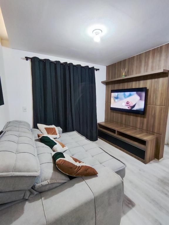 een woonkamer met een bank en een flatscreen-tv bij Apartamento aconchegante in Balneário Camboriú