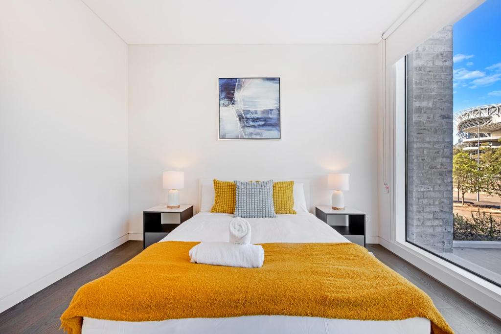 a bedroom with a large bed with a yellow blanket at Modern 3B2B apt with superb stadium view at sydney olympic park in Sydney