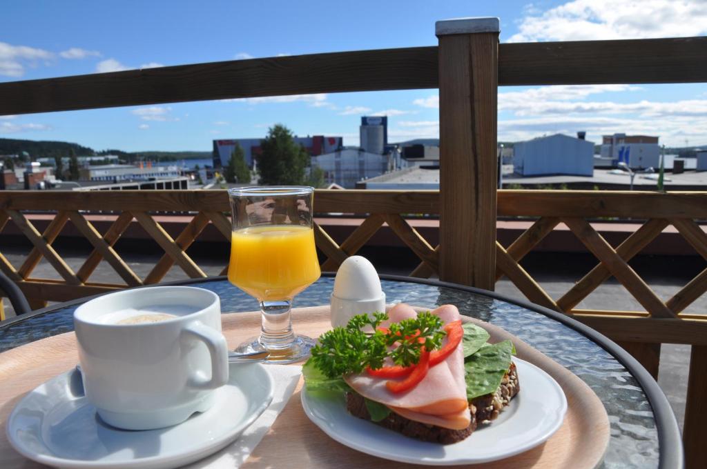 a table with a sandwich and a glass of orange juice at Strand City Hotel in Örnsköldsvik