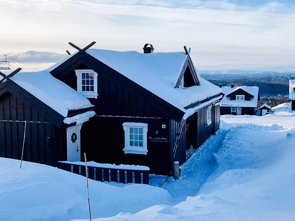 a black house is covered in snow at 9 person holiday home in Rauland in Rauland