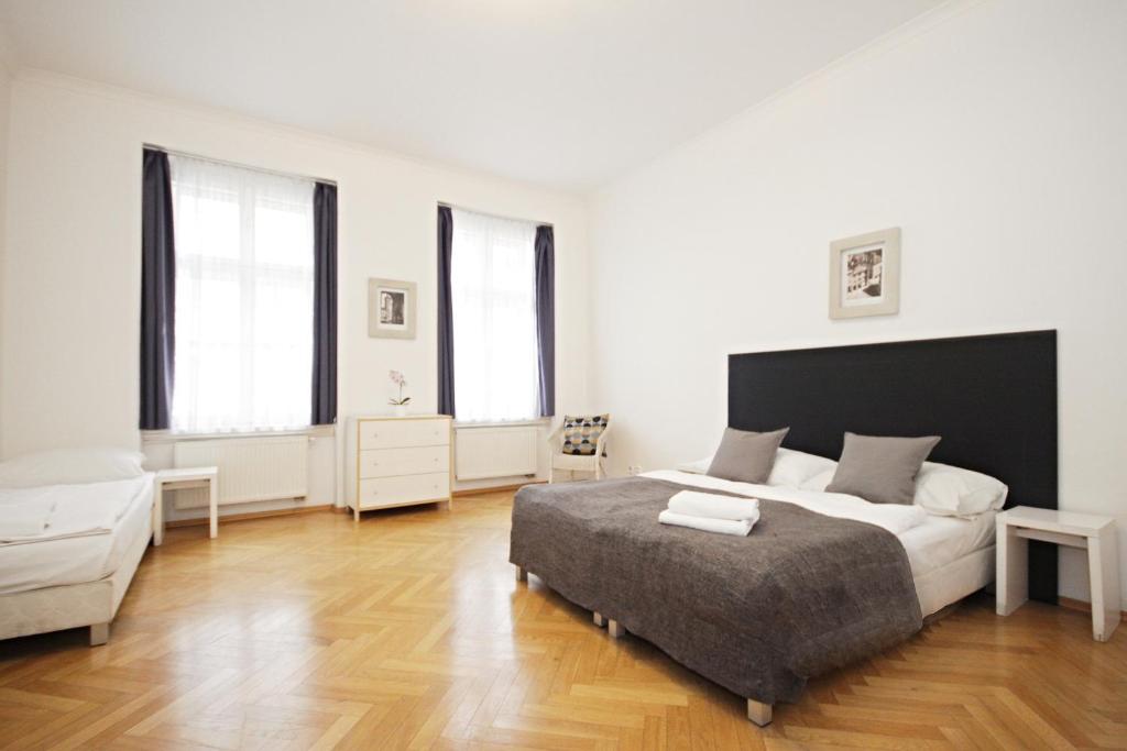 a white bedroom with a bed and two windows at Prague Central Residence in Prague