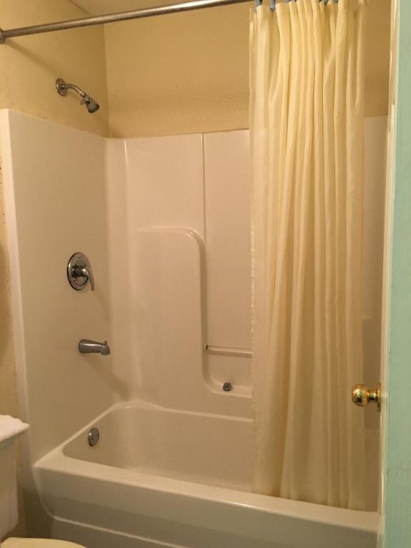 ein Bad mit einer Badewanne und einer Dusche mit einem Duschvorhang in der Unterkunft Garden Inn & Suites in Pensacola