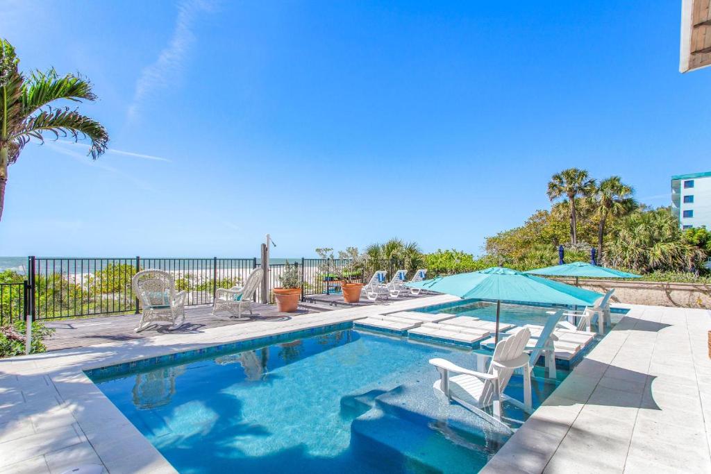 Una piscina con sillas y sombrillas y el océano. en Ocean Dream Villa, en Clearwater Beach