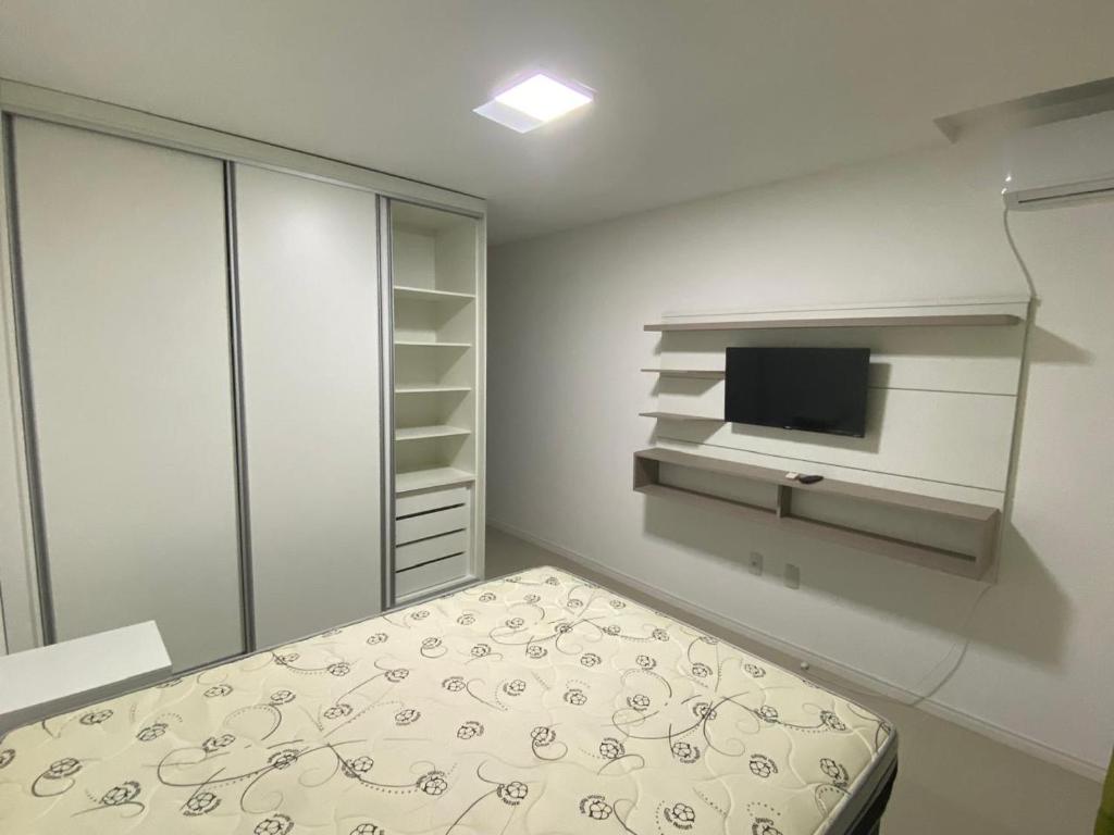 een witte slaapkamer met een bed en een televisie bij Apartamento Santa Clara in Balneário Camboriú