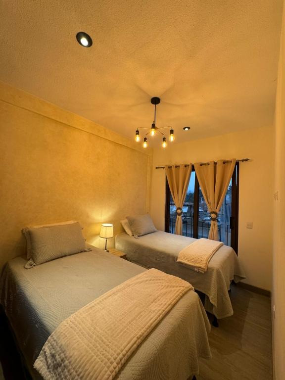 a bedroom with two beds and a window at Casa Grande de lujo cerca de Antigua Guatemala in Antigua Guatemala