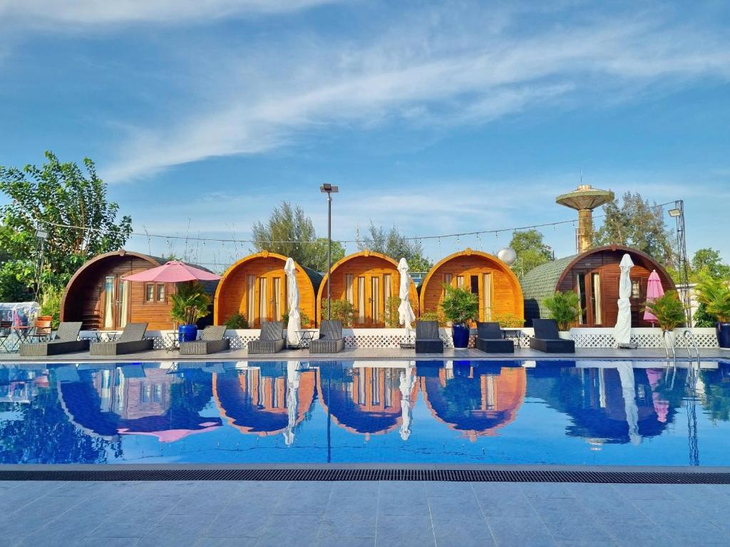 a pool at a resort with tables and chairs at Ruby Homestay Cần Giờ in Ấp Long An