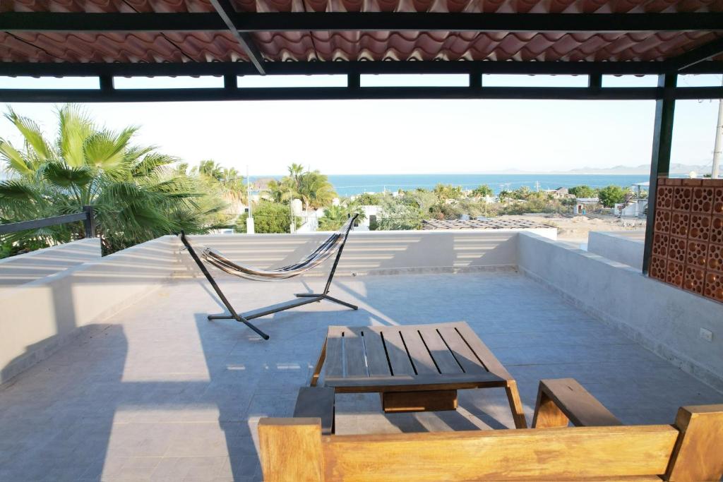 a patio with a hammock and a bench and the ocean at Casitas Punta Arenas #3 in La Ventana