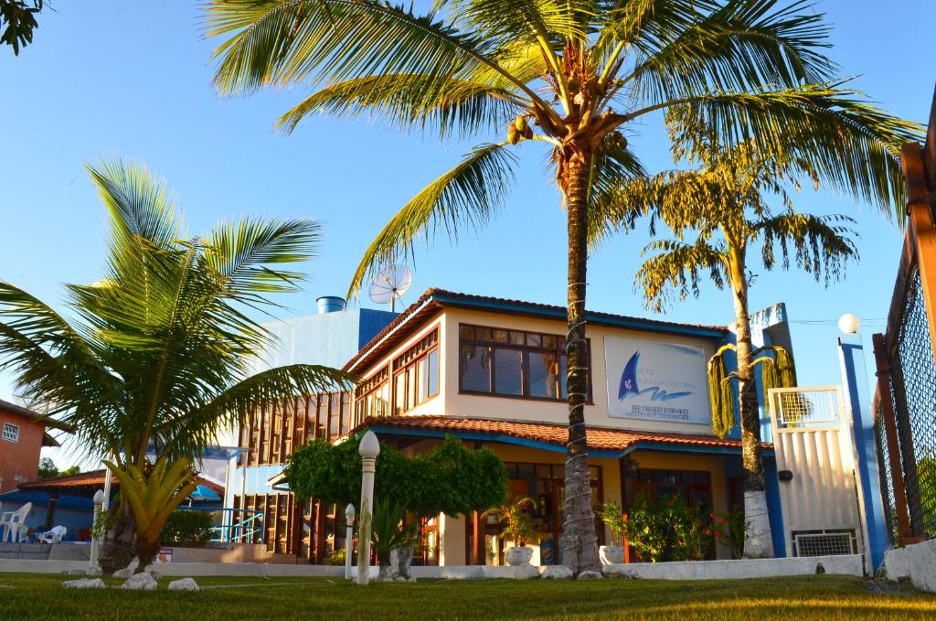 a building with palm trees in front of it at Hotel Porto das Ancoras in Porto Seguro