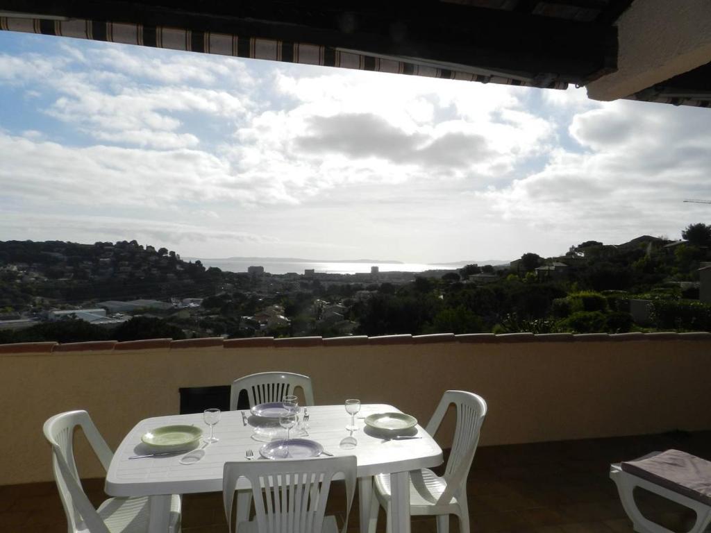 une table blanche et des chaises sur un balcon avec vue dans l'établissement Appt 2 pièces, terrasse 45m², parking, animaux acceptés - FR-1-251-855, à Bormes-les-Mimosas