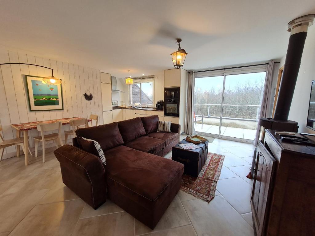a living room with a brown couch and a table at Gîte en Sologne avec Activités & Vol en Montgolfière - FR-1-590-550 in Jouy-le-Potier
