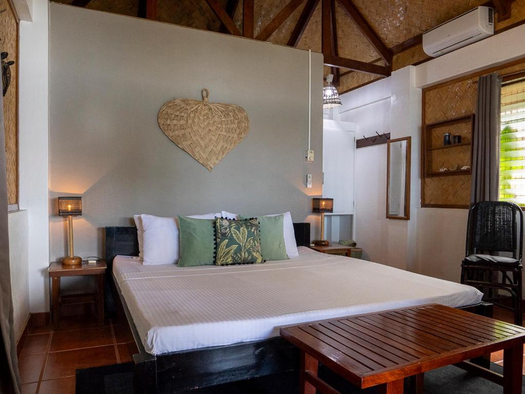 a bedroom with a bed and a heart on the wall at Golden Monkey Beach Hotel in El Nido
