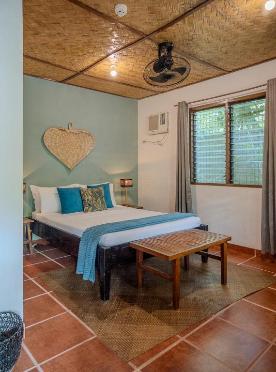 a bedroom with a large bed and a table at Golden Monkey Beach Hotel in El Nido