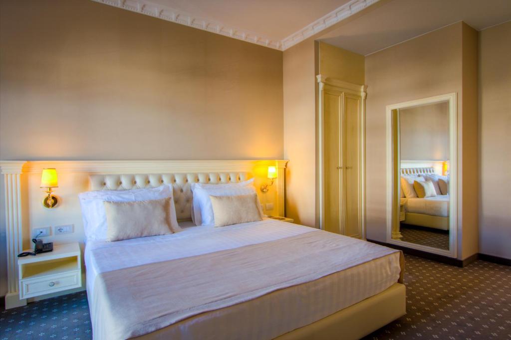 a bedroom with a large white bed with a mirror at Lot Boutique Hotel by Hotels and Preference in Tirana