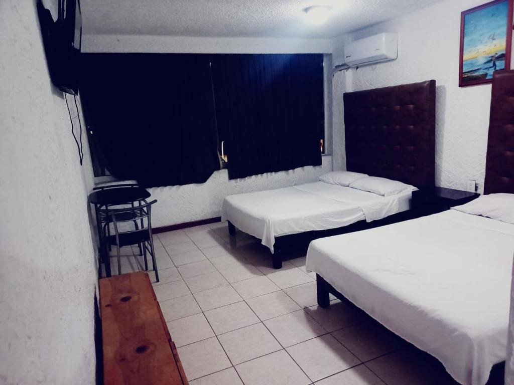 a bedroom with two beds and a table and a stool at Hotel Acuario in Acapulco