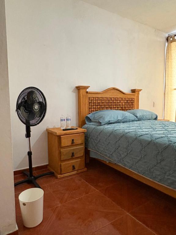 a bedroom with a bed and a fan and a dresser at casa los sabinos in Tepoztlán