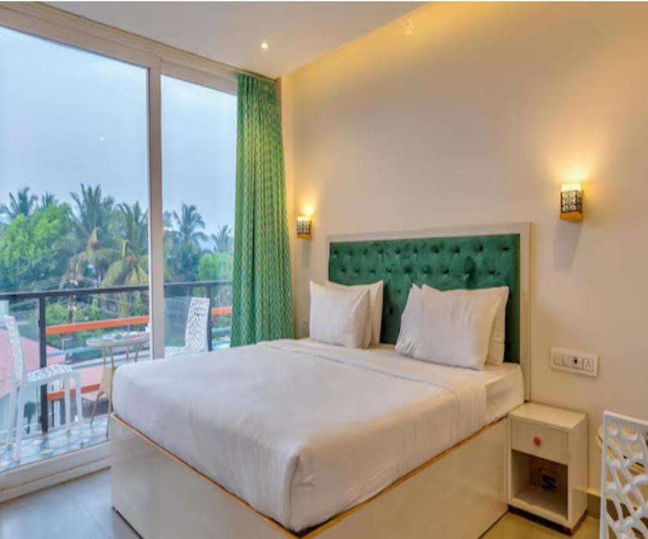 a bedroom with a large bed and a large window at The Luma House-TBV in Baga