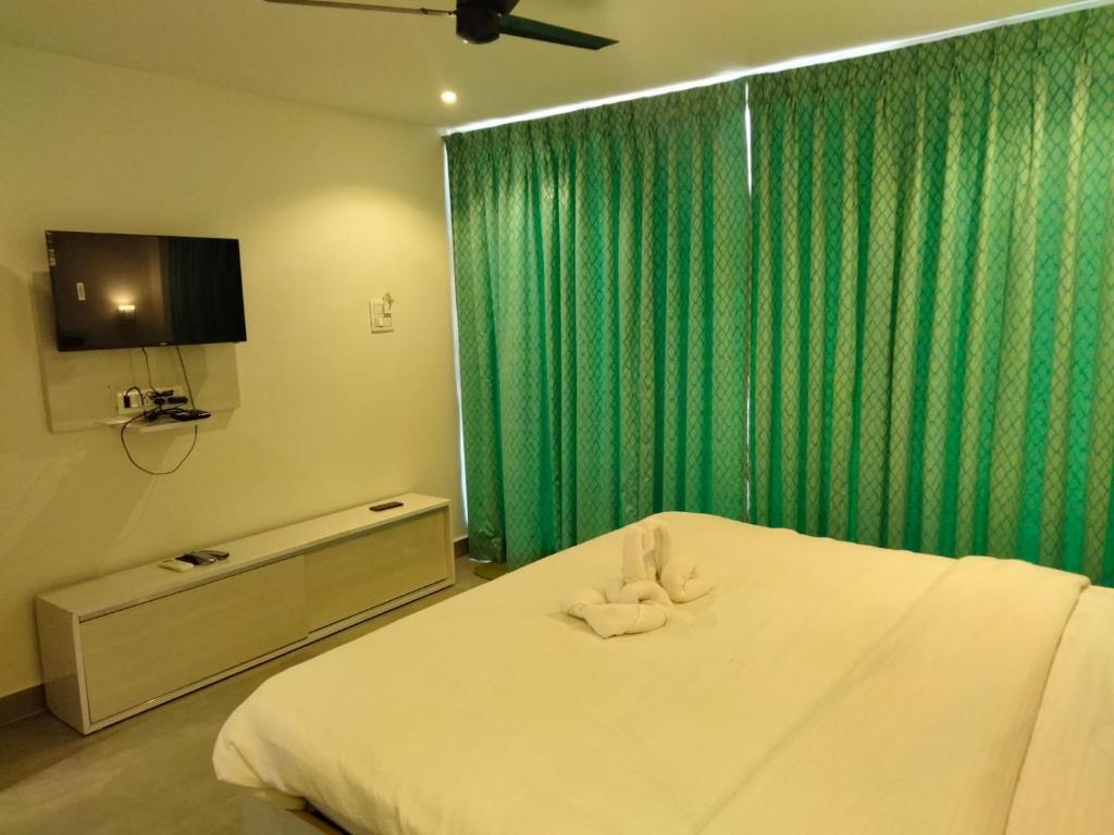 a bedroom with a white bed with a green curtain at The Luma House-TBV in Baga