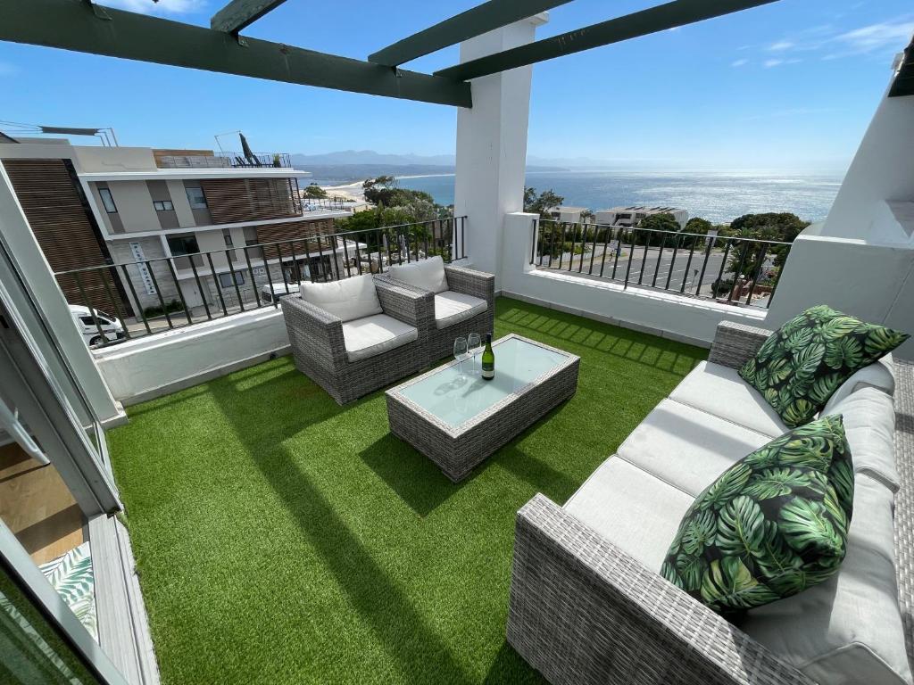 a patio with chairs and a table on a balcony at Hill Sea-View Apartment in Plettenberg Bay
