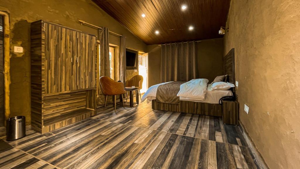 una camera con letto e pavimento in legno di Basho Mud Huts a Bashist