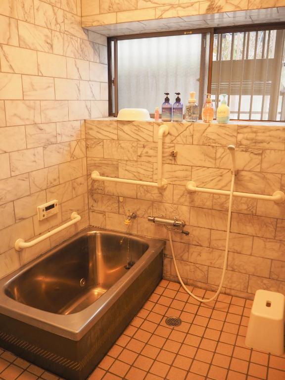 a bath tub in a bathroom with a sink at Guesthouse SETOUCHI LIFE in Kure