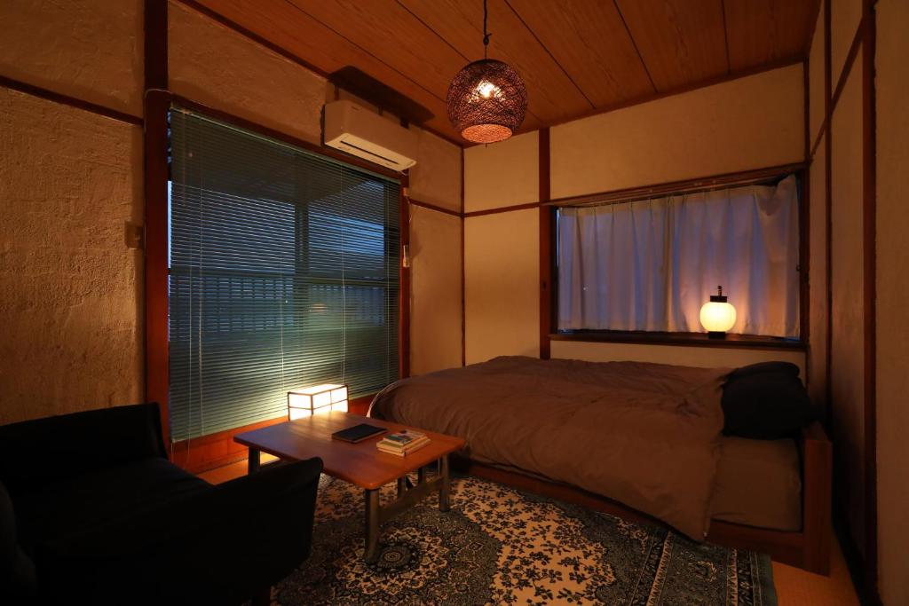 a bedroom with a bed and a table and a window at Guesthouse SETOUCHI LIFE in Kure