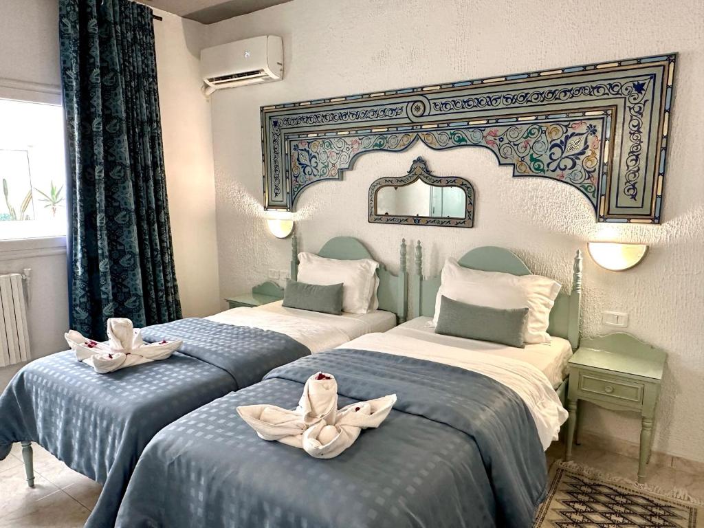 two beds in a hotel room with towels on them at Hotel Khella in Hammamet
