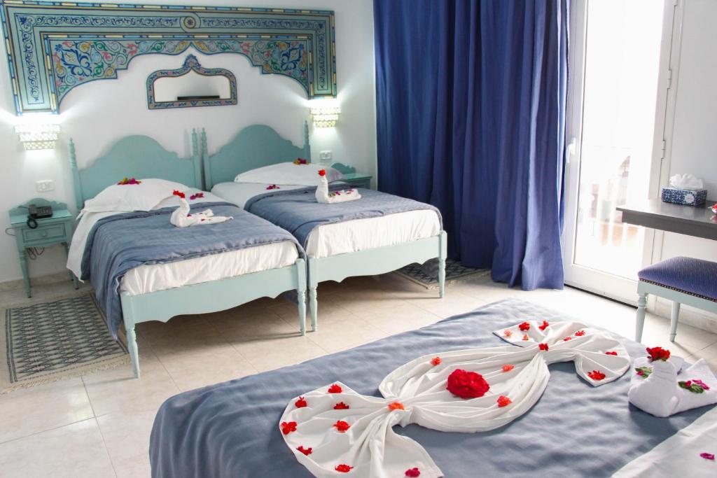 a bedroom with two beds with flowers on them at Hotel Khella in Hammamet