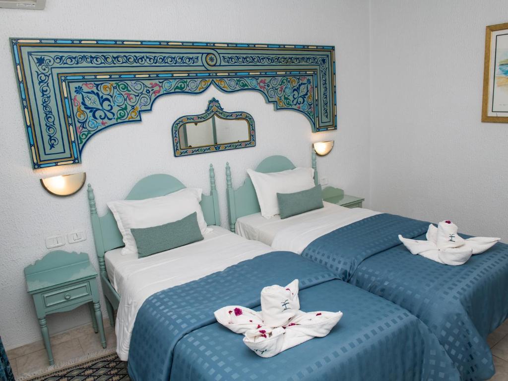 two beds in a room with blue and white at Hotel Khella in Hammamet
