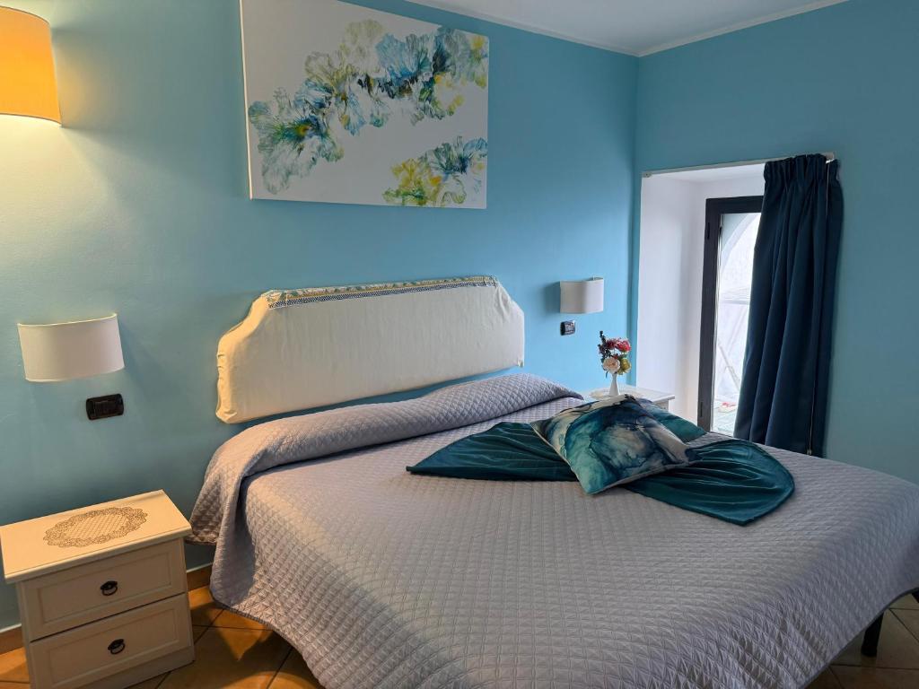 a bedroom with a bed with a blue wall at Luna Convento Copanello B&B in Stalettì