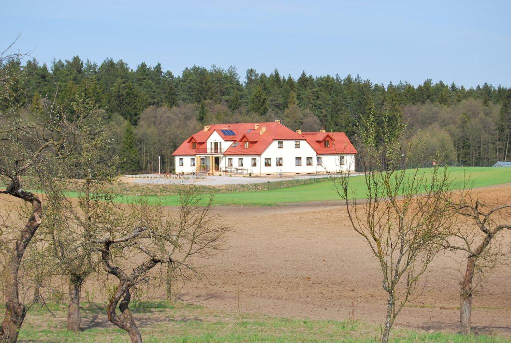 una grande casa bianca con un tetto rosso in un campo di Ośrodek Wypoczynkowy Sowa a Lipniak