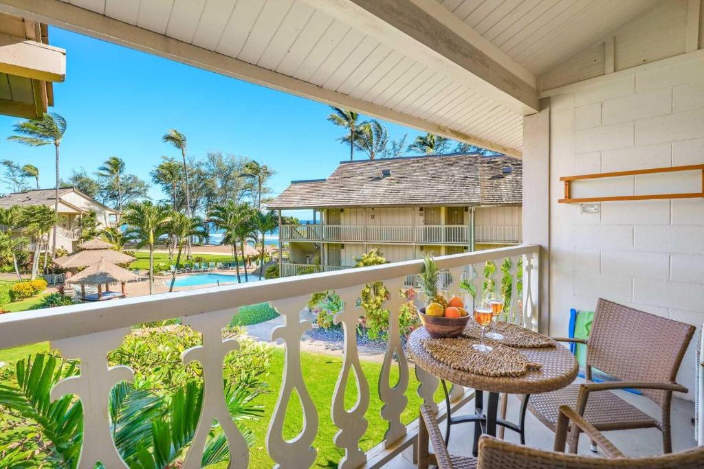 a balcony with tables and chairs and a view of a resort at Islander on the Beach 343 in Kapaa