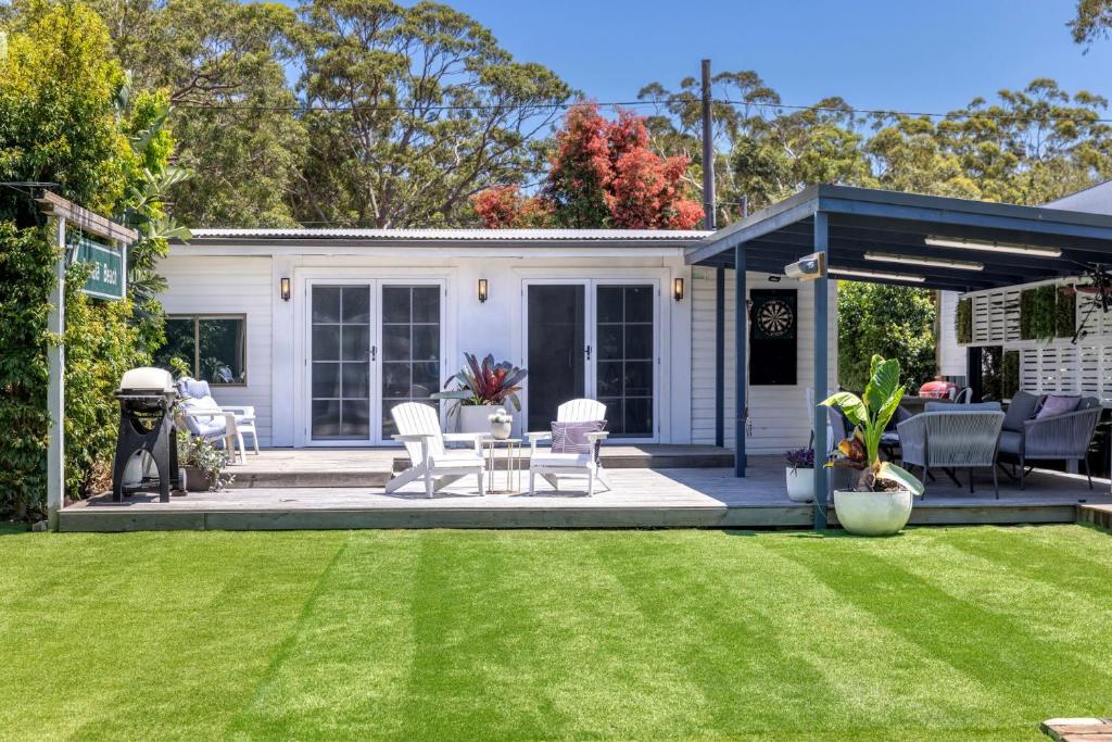 a house with a yard with chairs and a patio at A Touch Of Paradise - 4 MIn Walk to Beach in Callala Beach