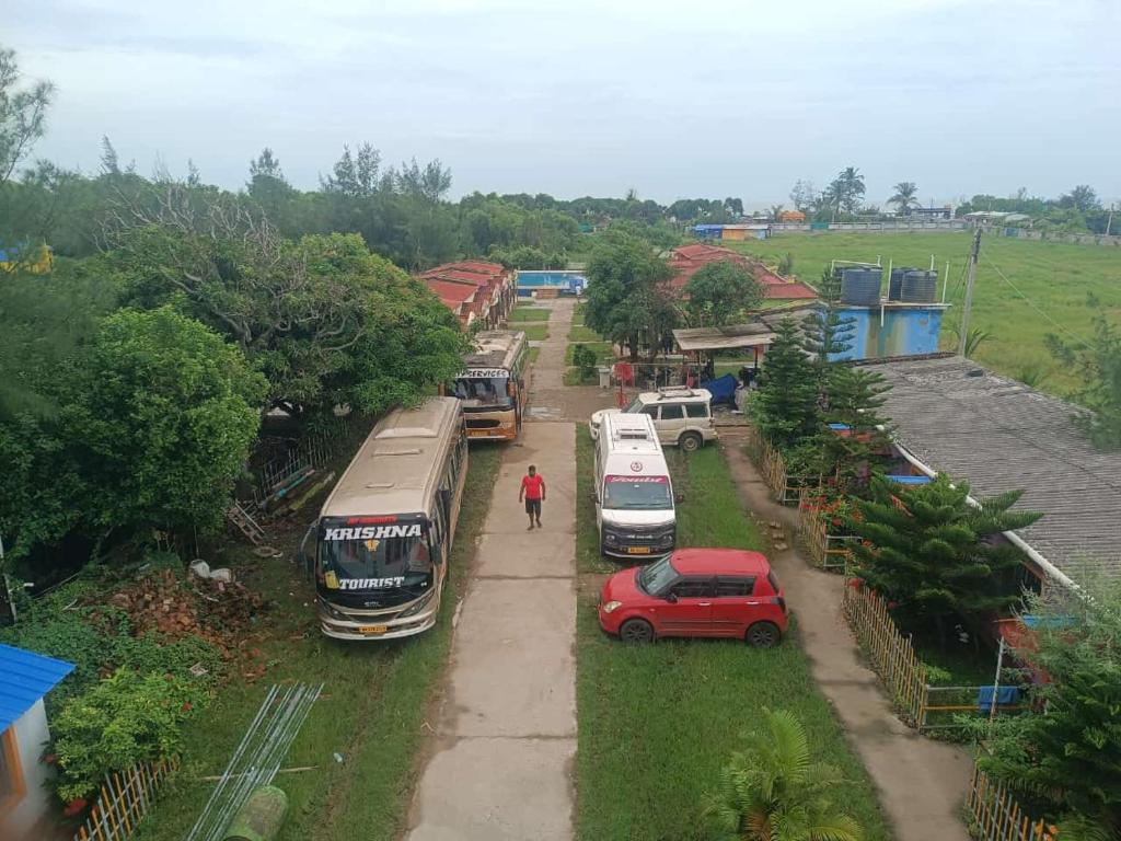 un grupo de autobuses y un coche rojo en una calle en Star inn resort, en Tajpur