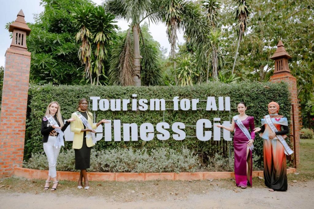 Un gruppo di donne che si trovano davanti a un cartello di Srichaiyapura Wellness Resort a Ban Tha Phaniat