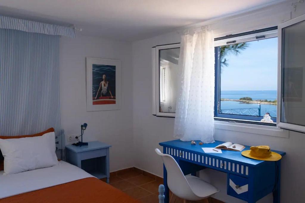 een slaapkamer met een blauw bureau en een raam bij Blue Marina in Sivota