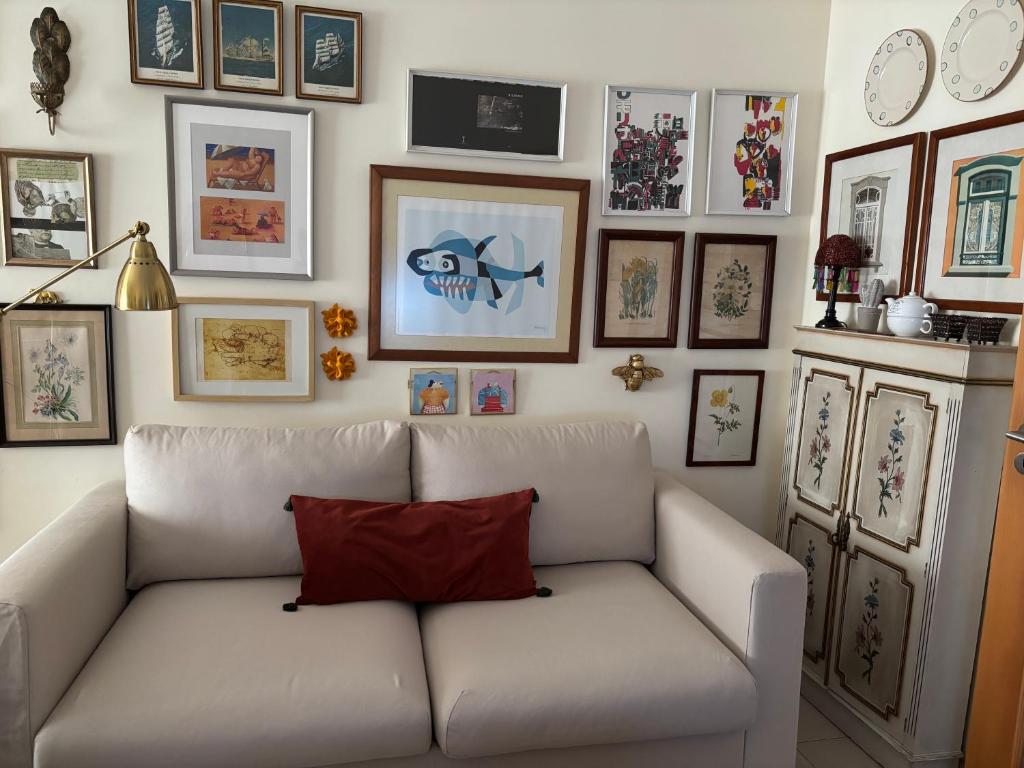a living room with a white couch and pictures on the wall at Lua do Mar - T2 - Piscina - Fte ao Mar- Central in Nazaré