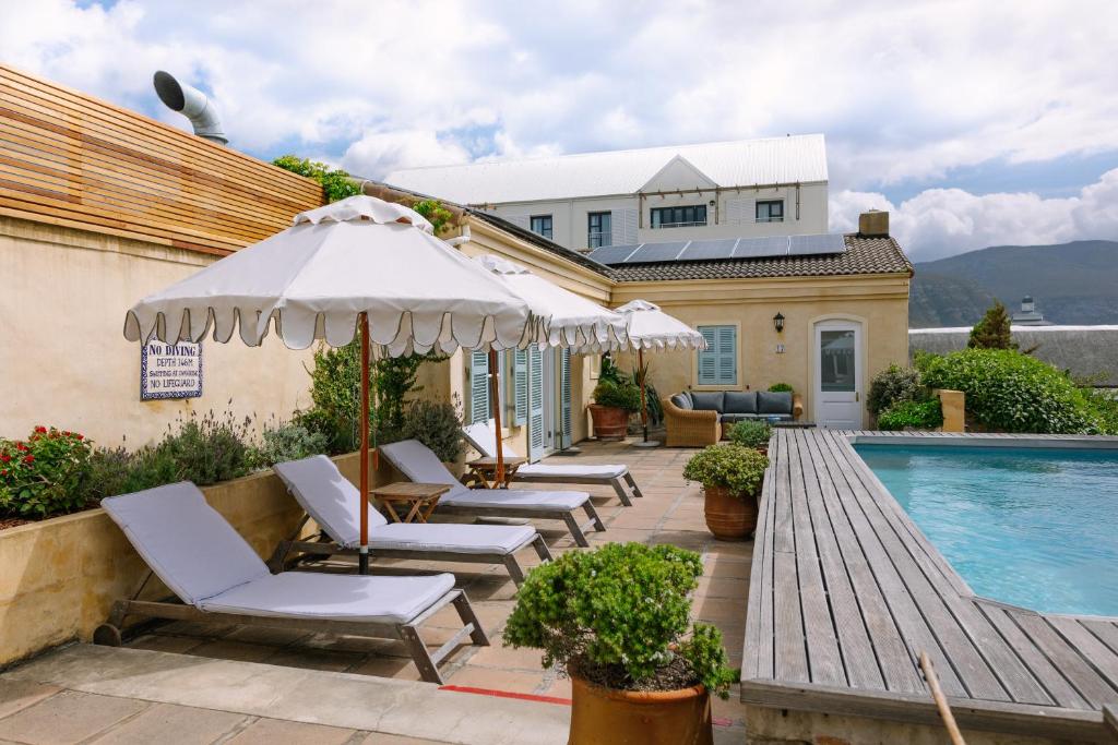a patio with chairs and an umbrella next to a swimming pool at Auberge Burgundy Boutique Hotel & Spa in Hermanus