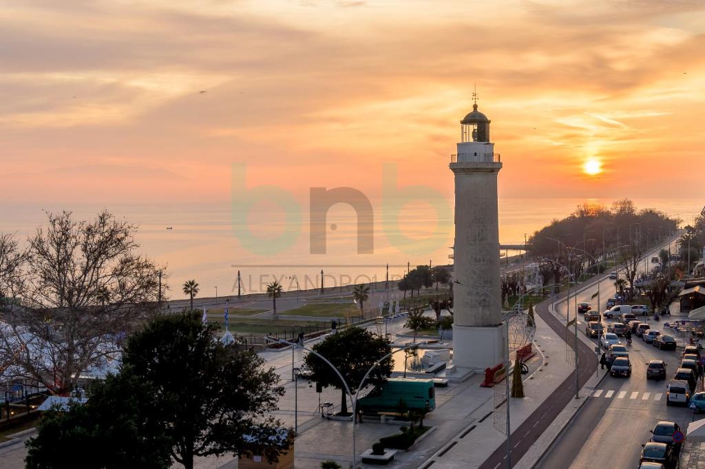 a lighthouse on a city street with a sunset in the background at Sea view luxury apartment in Alexandroupoli