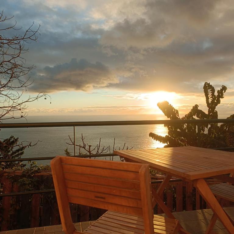 un tavolo in legno e una panca con il tramonto sullo sfondo di Casa Bela Vista Studio 1 a Ribeira Brava