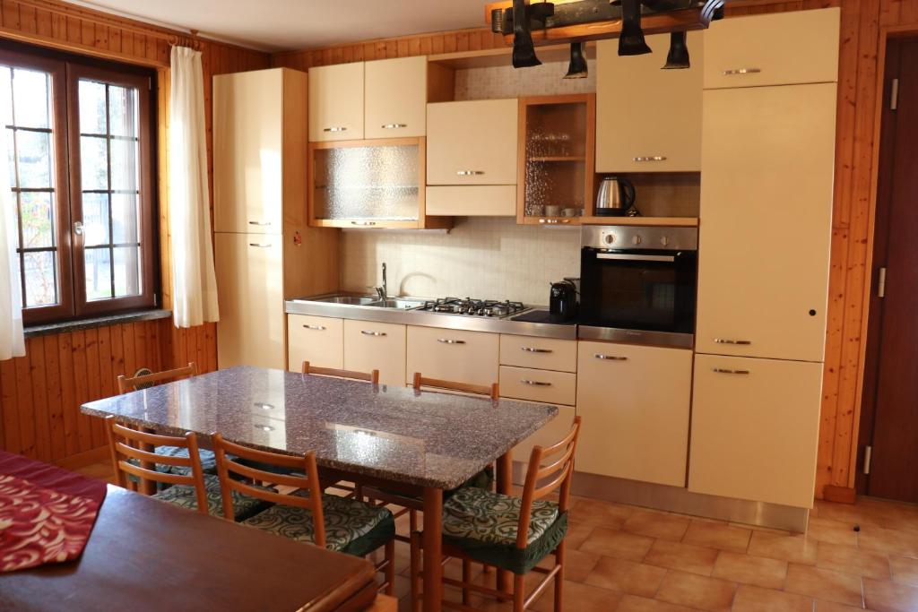 y cocina con mesa, sillas y fogones. en La casa di Juliette, en Merone