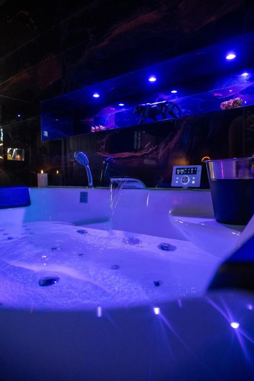 - une baignoire blanche avec des lumières bleues dans la chambre dans l'établissement Baobab, à Corbas