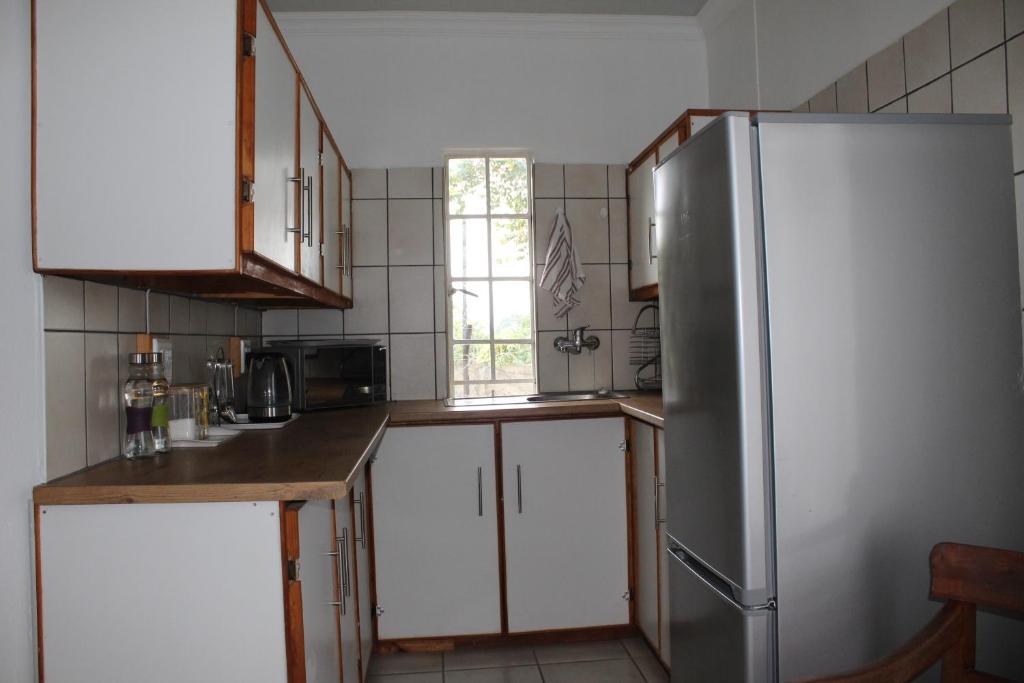 eine Küche mit weißen Schränken und einem Edelstahlkühlschrank in der Unterkunft Angel Cottage in Tzaneen