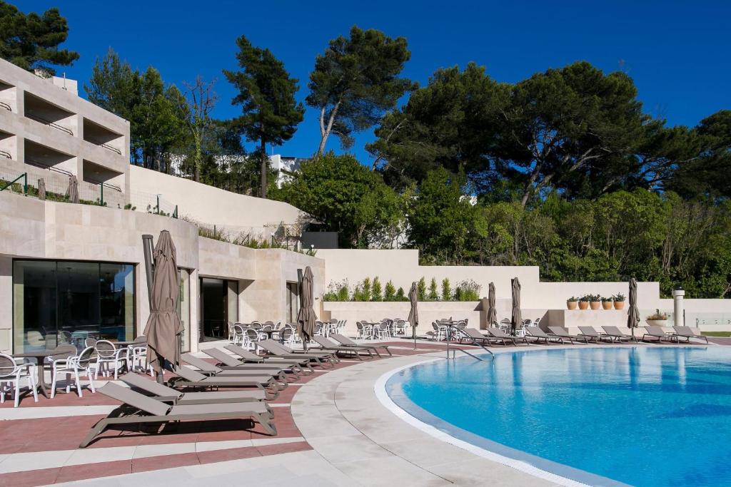 een zwembad met ligstoelen en een resort bij Four Points by Sheraton Sesimbra in Sesimbra