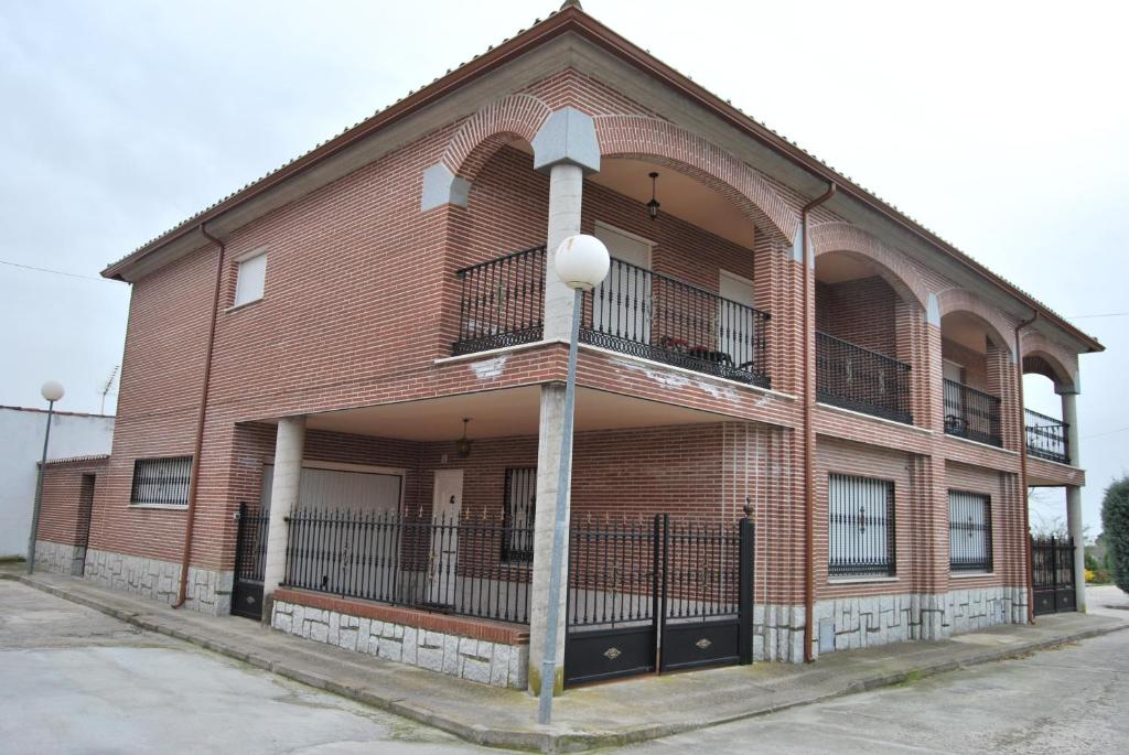 un edificio de ladrillo con un balcón en el lateral. en Casa Rural La Malena, en Cazalegas