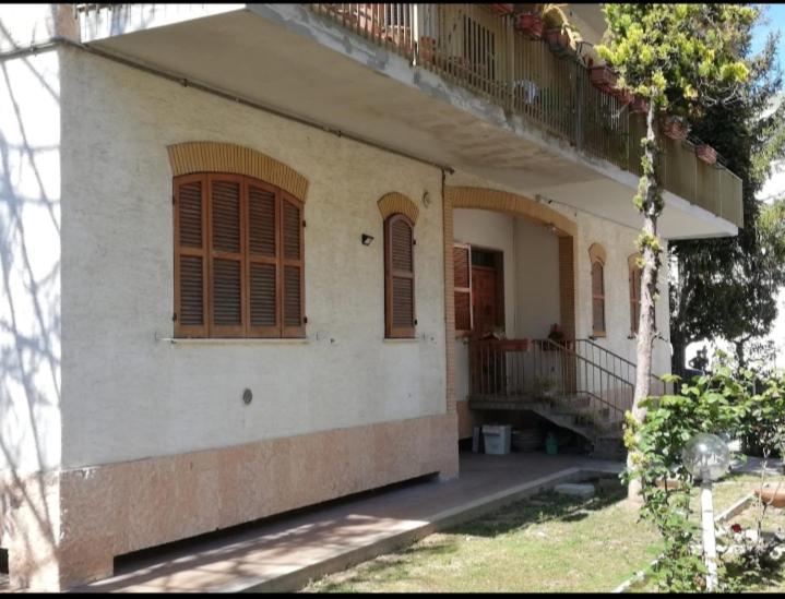 a white house with brown shutters and a balcony at La casa di Lilia in Francavilla al Mare