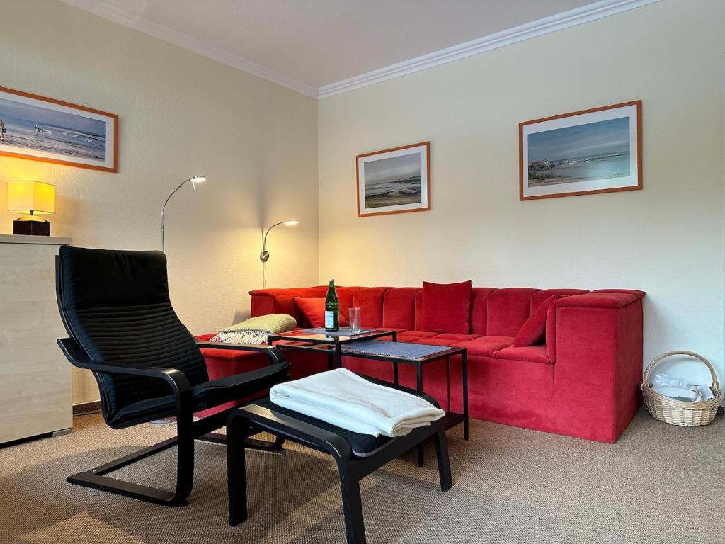 a living room with a red couch and a table at Küsten Koje in Sankt Peter-Ording