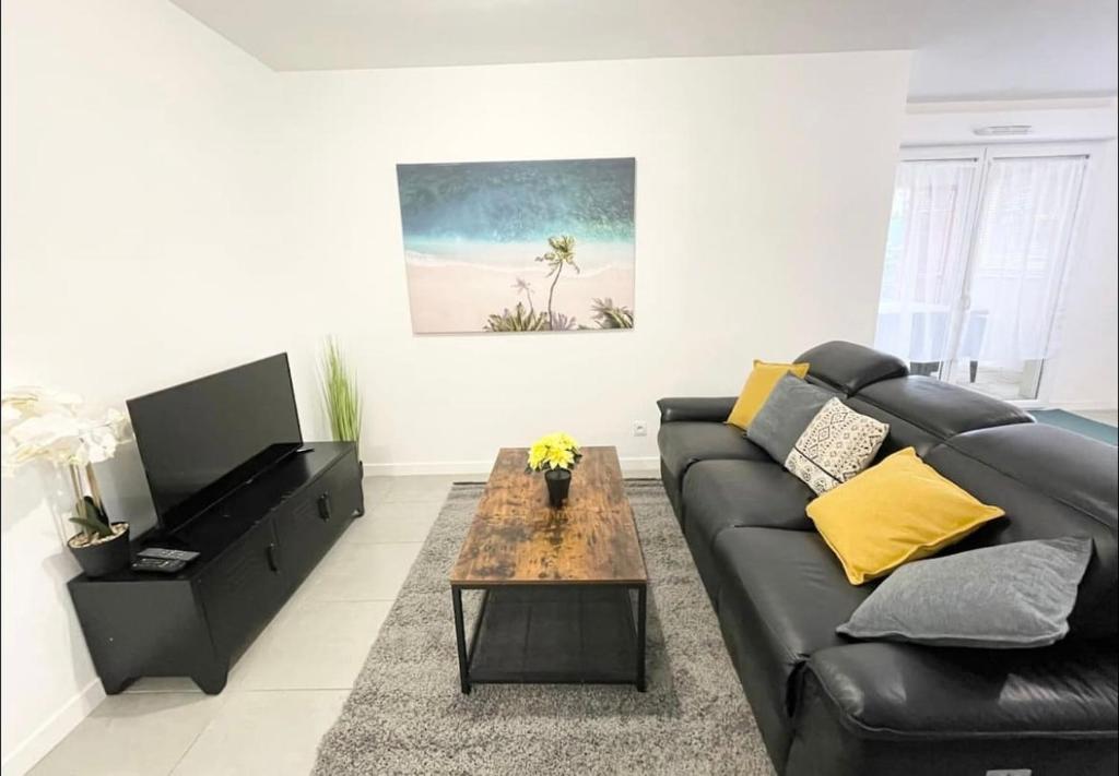 - un salon avec un canapé en cuir noir et une table basse dans l'établissement Appartement - Le Salengro, à Villeurbanne