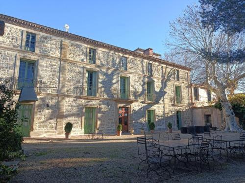 - un grand bâtiment en pierre avec des chaises en face dans l'établissement Domaine de la Clapière, à Montagnac